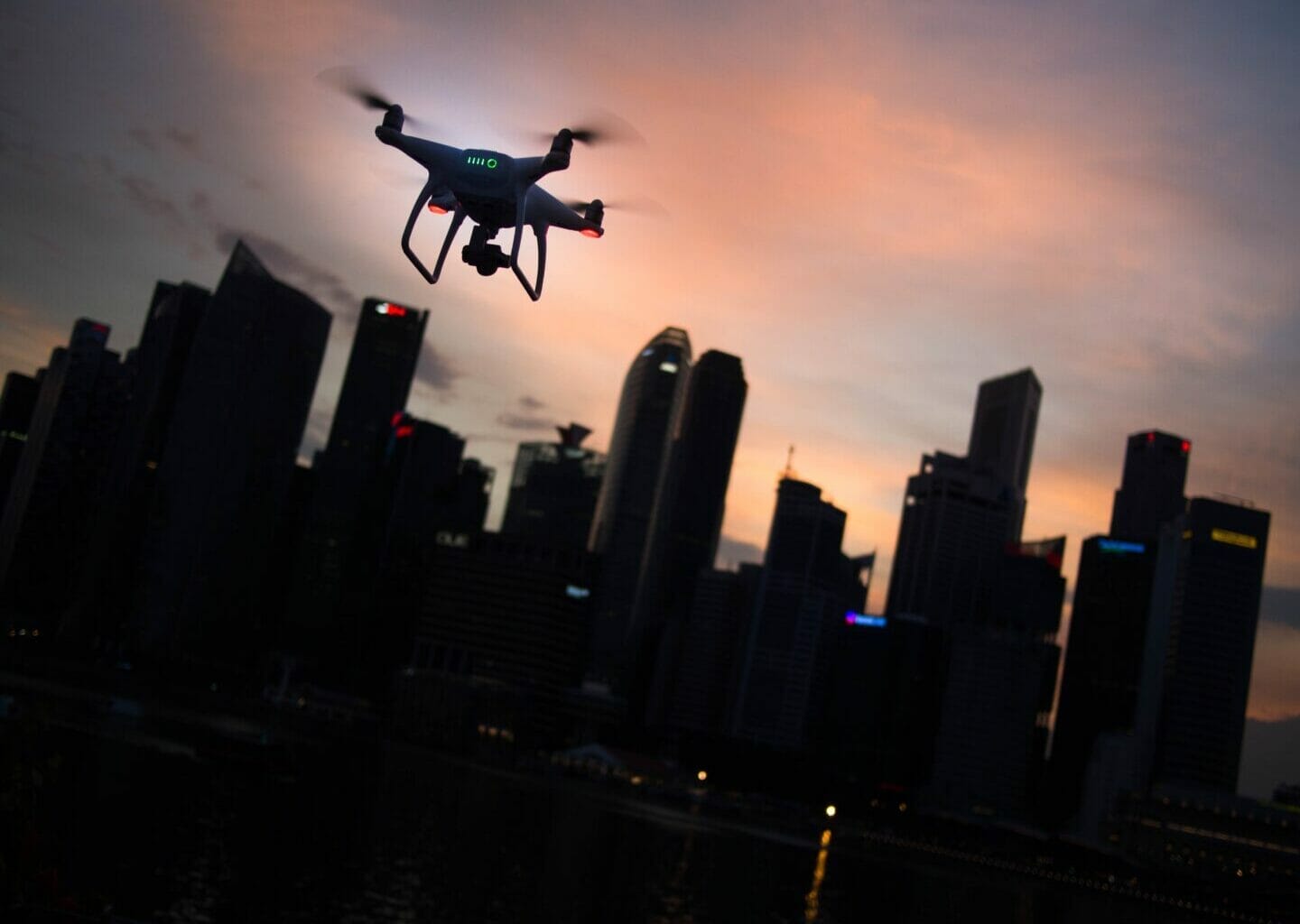 silhouette of quadcopter drone hovering near the city